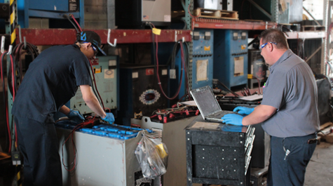 Employees working on forklift battery at DC Power Solutions.